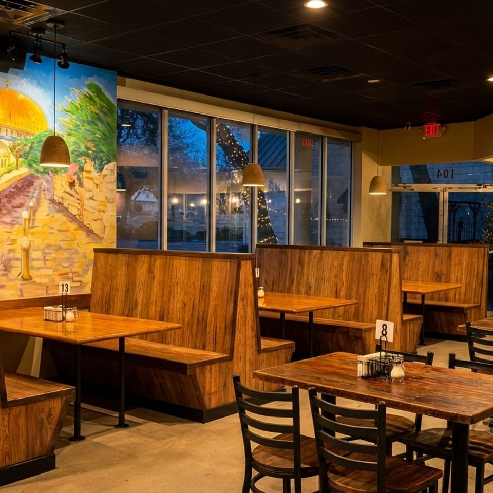 Restaurant interior with wooden booths and tables, a mural of the Dome of the Rock, and large windows.